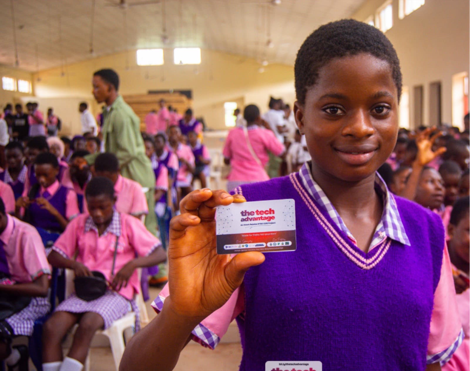 A student at Idia College holding up her TTA card
